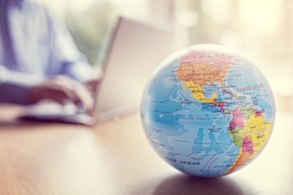 Close-up of a globe with a person working on a laptop in the background, symbolizing Mocean SMS messaging campaign solutions empowering Singaporean businesses globally.