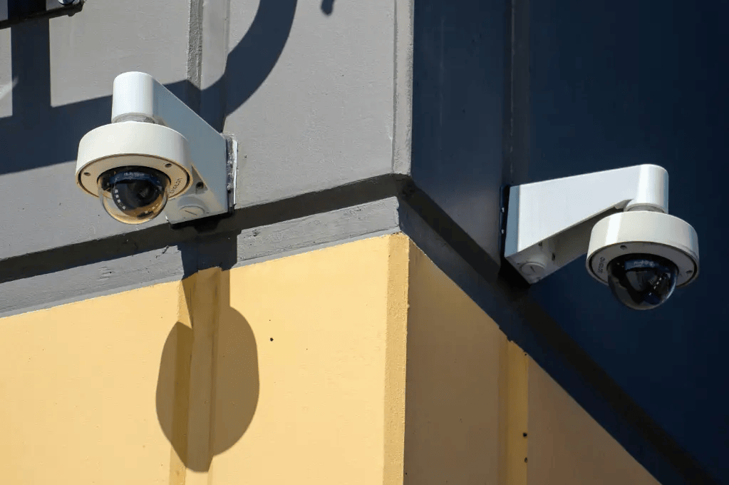 Security cameras on a building wall symbolizing Mocean SMS messaging campaign for authentication, fraud alerts, and account verification.